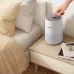 Bedroom view of Philips 600i Series Air Purifier showing hand pressing power button beside books on a bedside table.