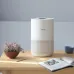 Tabletop view of Xiaomi Smart Air Purifier 4 Compact beside plant, cup, and magazine in minimalist home setting.