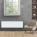 Interior view of Tesy CN 06 060 EA FinEco Cloud Heater mounted on gray wall beside armchair and shelf.