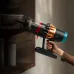 Side view of Dyson V16 Piston Vacuum Cleaner in handheld mode cleaning shelf with transparent bin and gold-red accents.