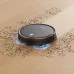Action view of Xiaomi E5 Robot Vacuum Cleaner cleaning debris on wooden floor with blue lights under suction area.