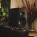 ADAM Audio T7V Studio Monitor Speaker placed beside a computer setup in a warm, ambient workspace.