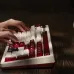 Close-up of hands typing on 8BitDo Retro 108 Keyboard with retro red and white keycaps highlighted in dramatic lighting.