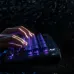 Close-up of hands typing on 8BitDo Retro 87 Keyboard with illuminated purple backlighting in dark setting.