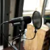 Close-up of the black Shure MV7X microphone on a stand, positioned with a pop filter/shield.