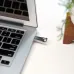 Close-up of the PNY Elite-X Pen Drive inserted into a silver laptop USB port with visible keyboard and desktop decor.