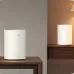 Two white cylindrical Cudy M3600 BE3600 mesh Wi-Fi nodes placed on different wooden tables in a living space.