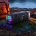 The Soundcore Boom 3i speaker sits on a rock outdoors, with its colorful LED lights illuminating the surroundings.