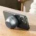 Top-down view of Awei KA53 Mini Bluetooth Speaker attached to smartphone camera area showing circular grip accessory design.
