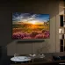 An angled view of the Samsung 43Q65D 4K QLED Smart TV and soundbar mounted on a wall, displaying a vibrant sunset over a field of horses.