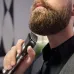 Lifestyle view of Philips MG9553/15 Trimmer used under chin with metallic body, green power button, and ergonomic black grip.