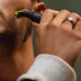 Lifestyle view of Philips OneBlade QP1424/10 Trimmer in use, trimming facial hair along cheek with bright green blade head.